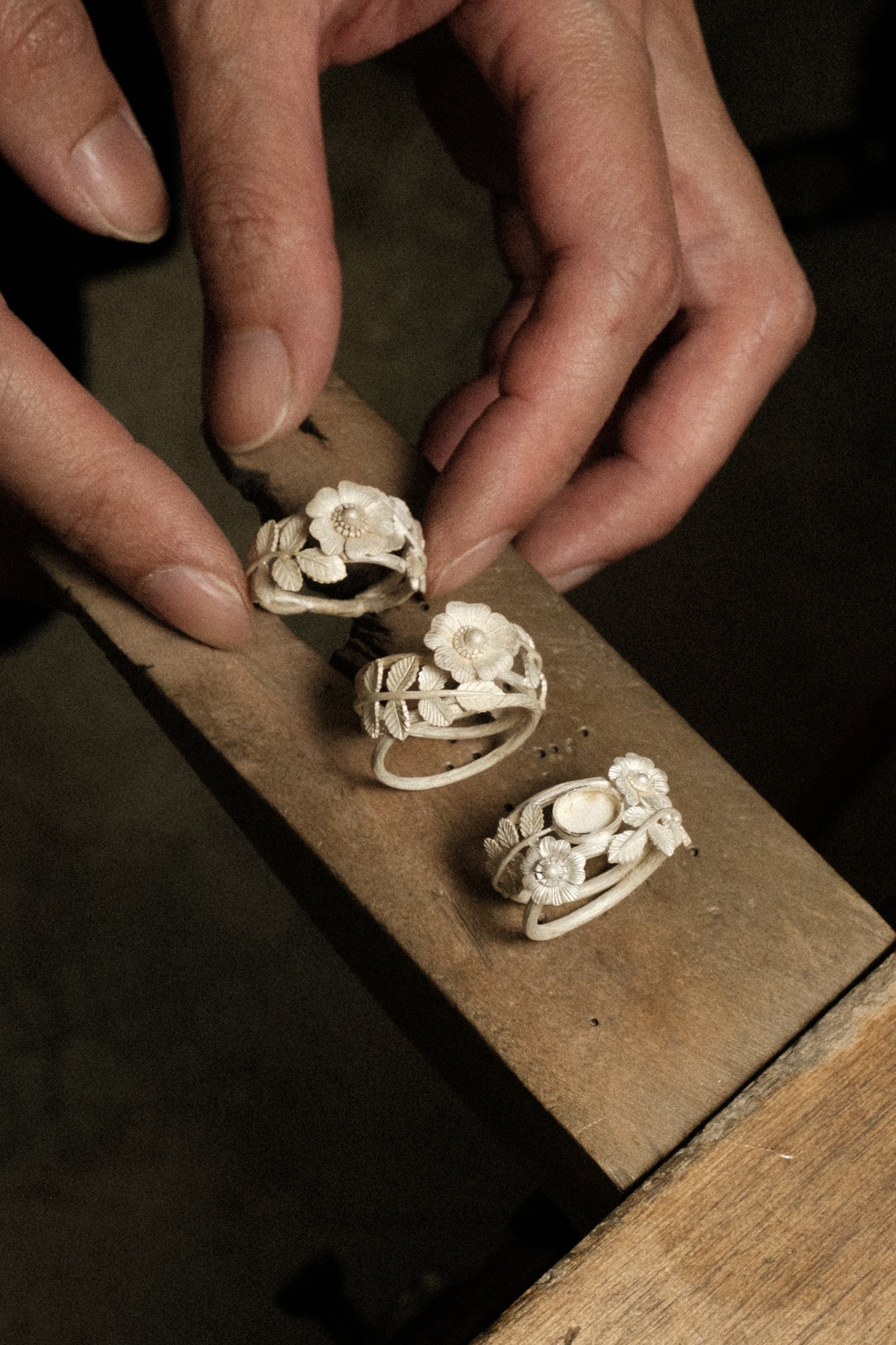 A jeweler’s bench displaying three raw white 925 sterling silver in botanical rosa design inspired by nature.