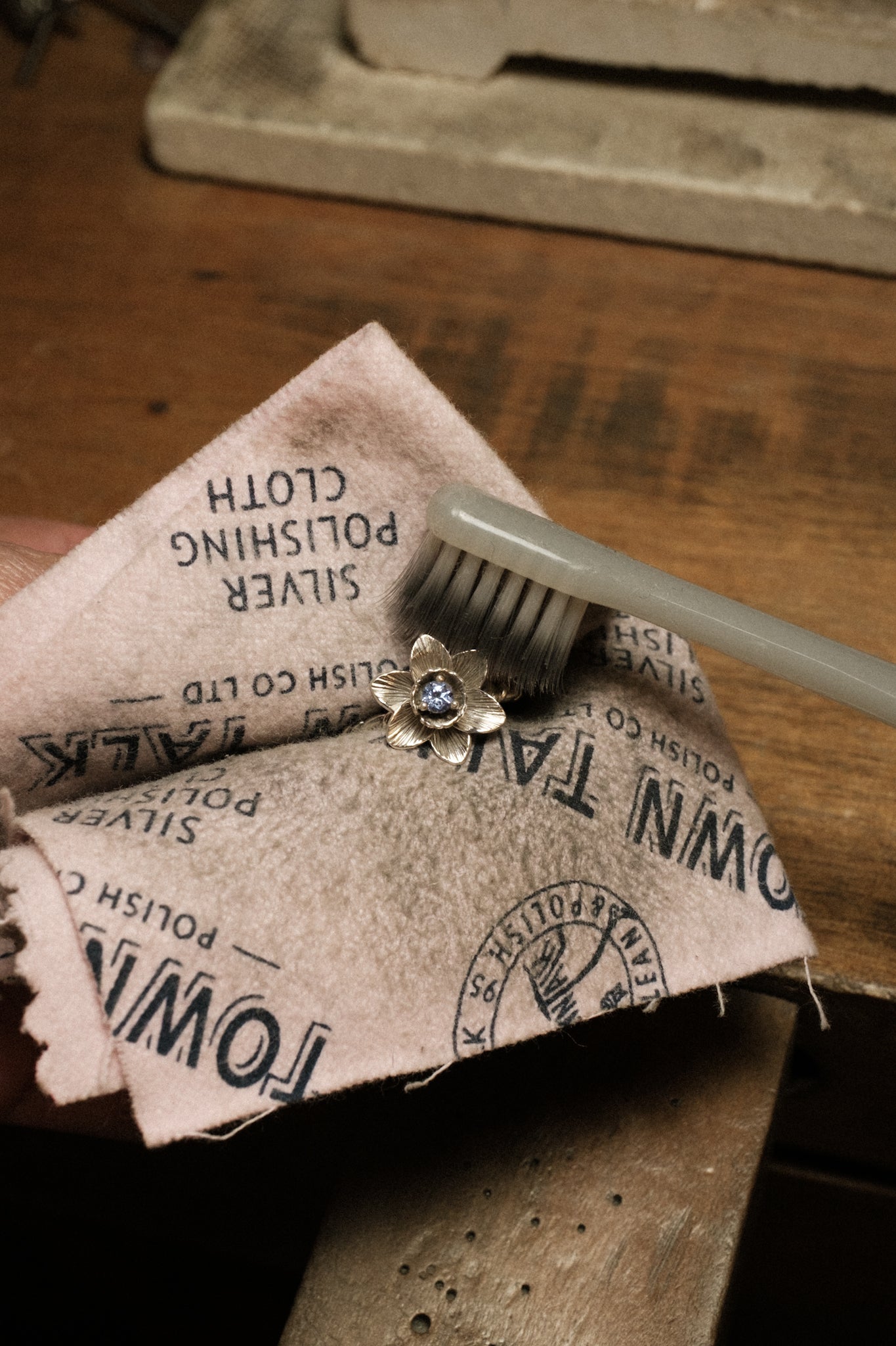 Using a Town Talk brand silver cleaning cloth to wipe clean a 925 sterling silver ring in floral design, inspired by botanical nature.