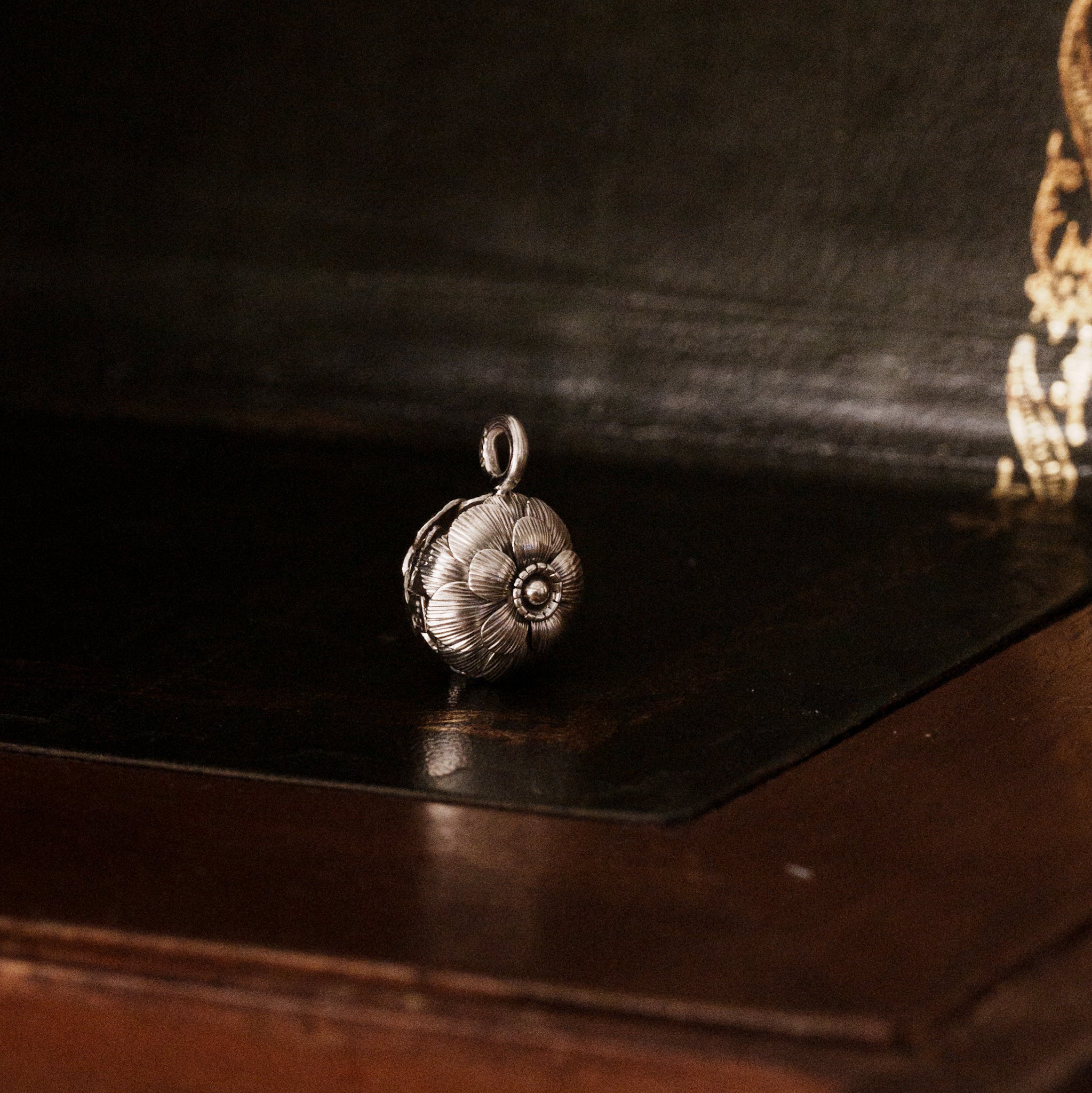 Showing details of a 925 sterling silver camellia flower-shaped pendant on a dark wooden surface