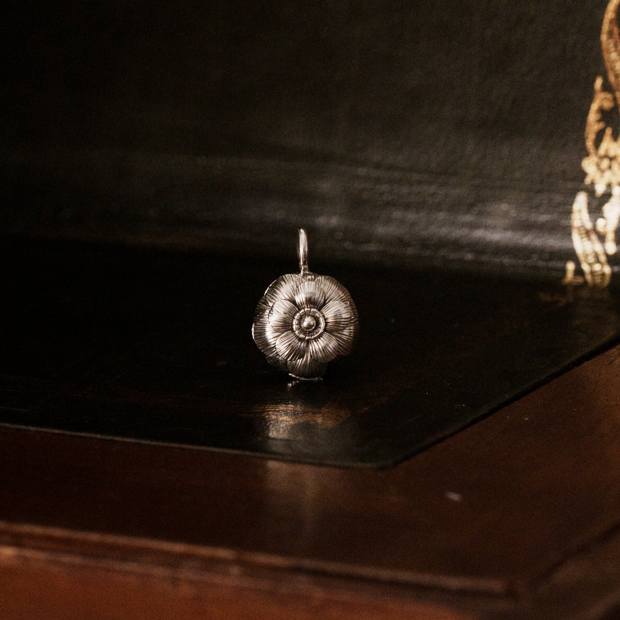 Front view of a 925 sterling silver camellia flower-shaped pendant on a dark wooden surface