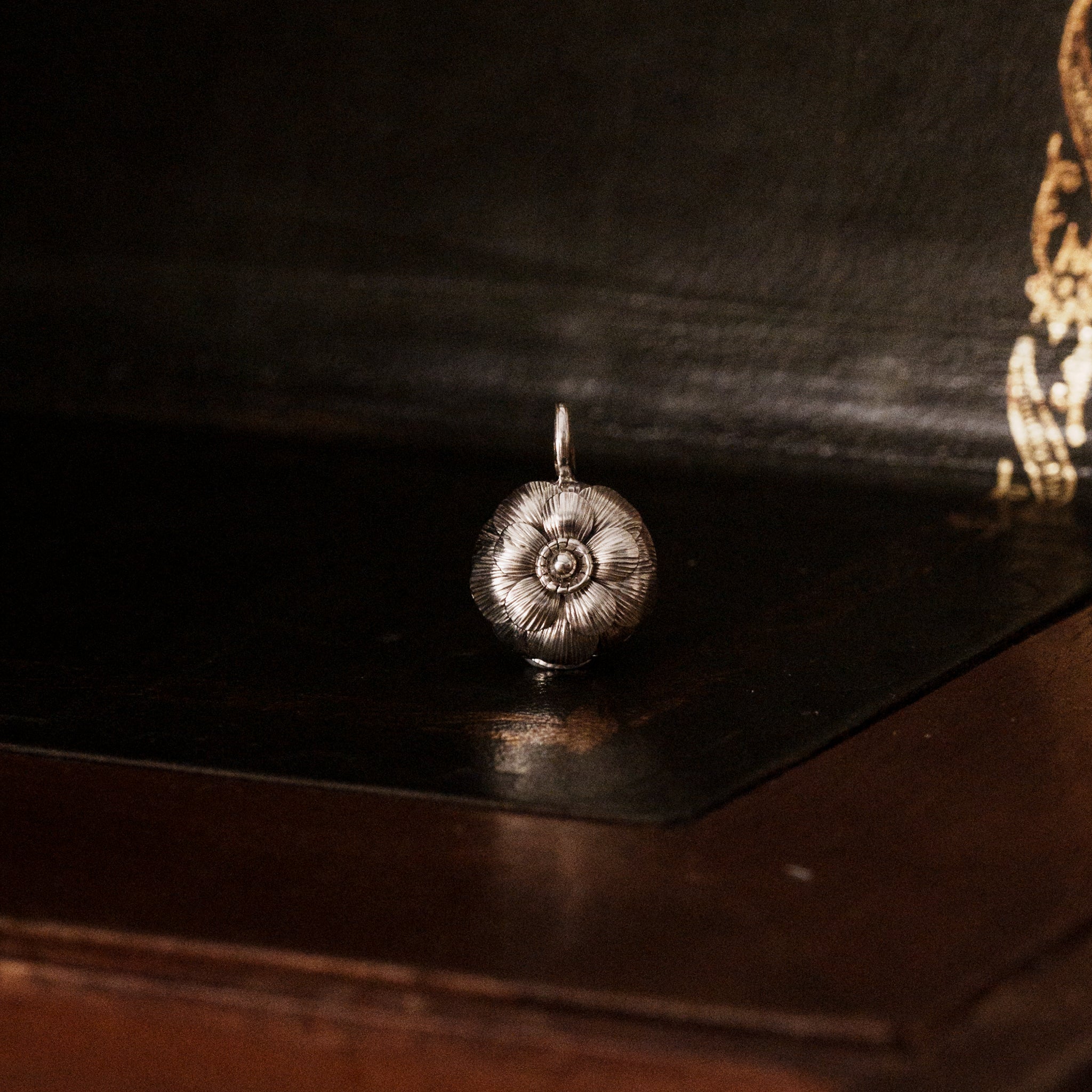 925 sterling silver camellia flower-shaped pendant on a dark wooden surface