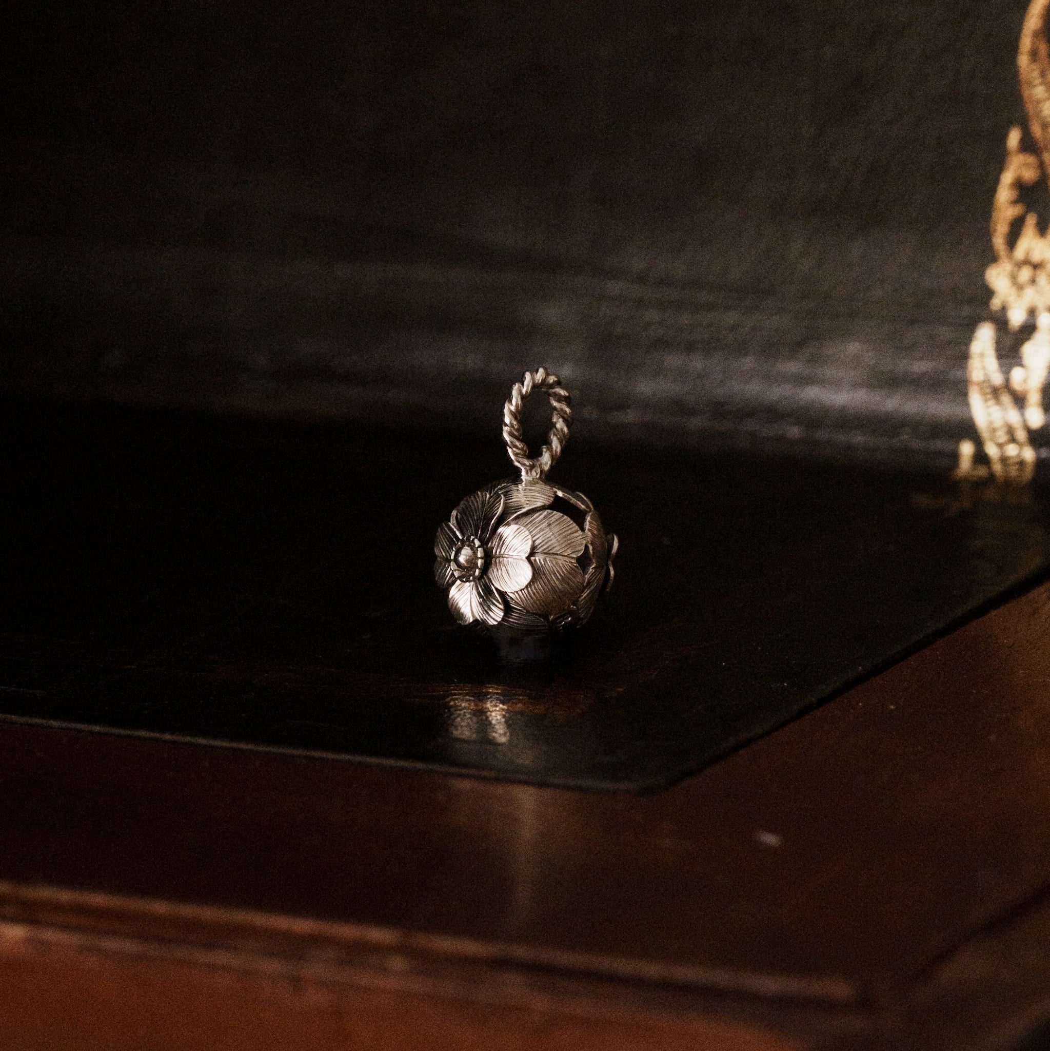 925 sterling silver four leaf clover shaped pendant on a dark wooden surface showing multiple layers of leaf details