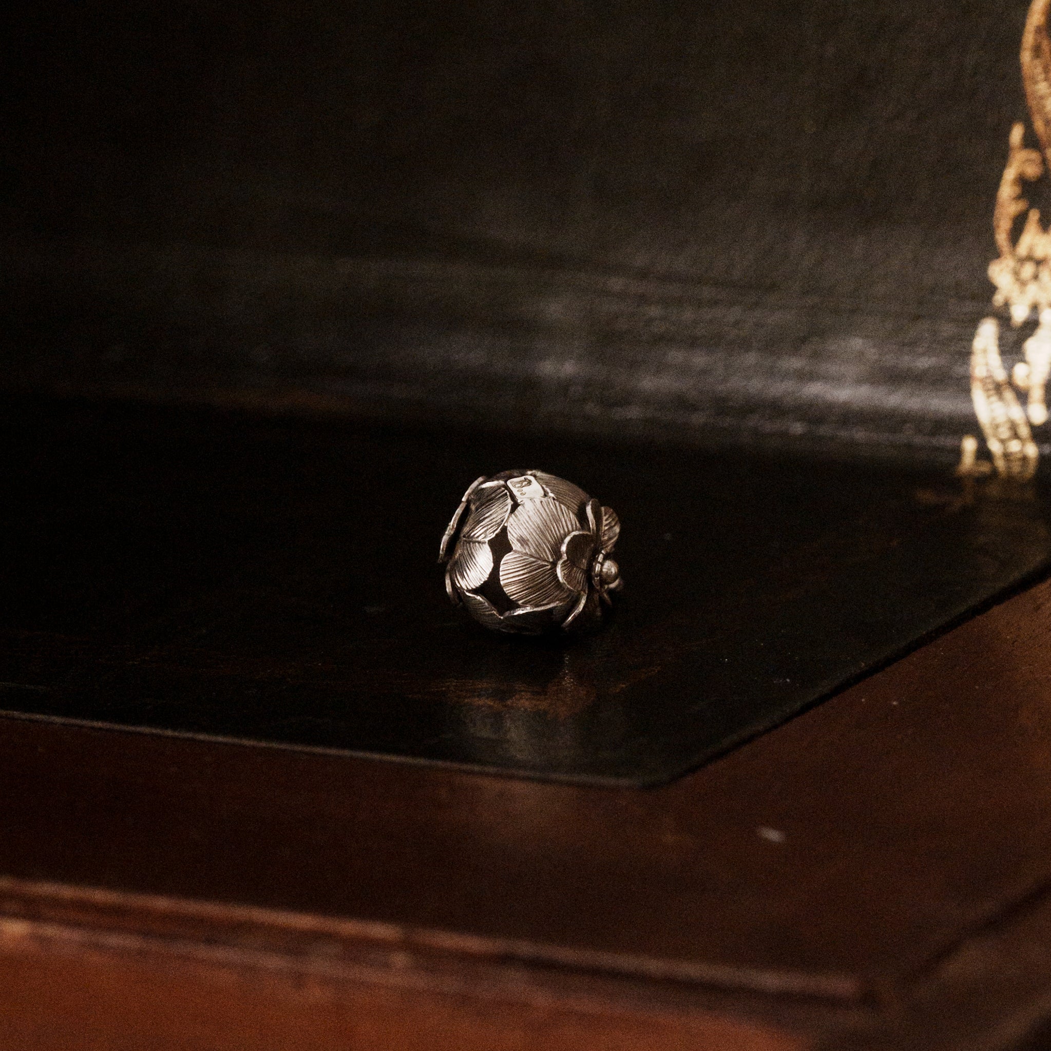 a 925 sterling silver four leaf clover shaped pendant lying down on a dark wooden surface, showing the brand's logo tag