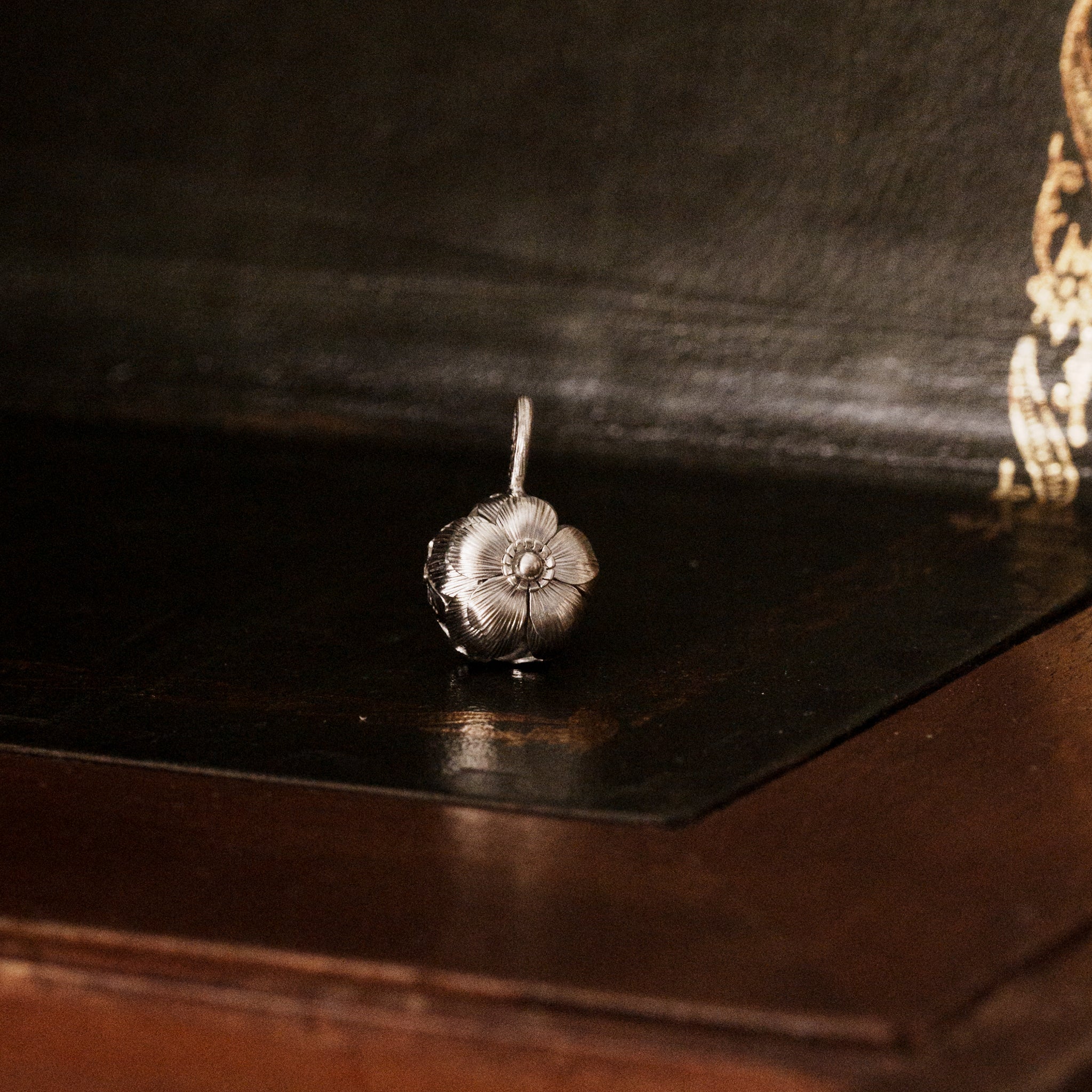 Front view of a 925 sterling silver sakura flower-shaped pendant on a dark wooden surface