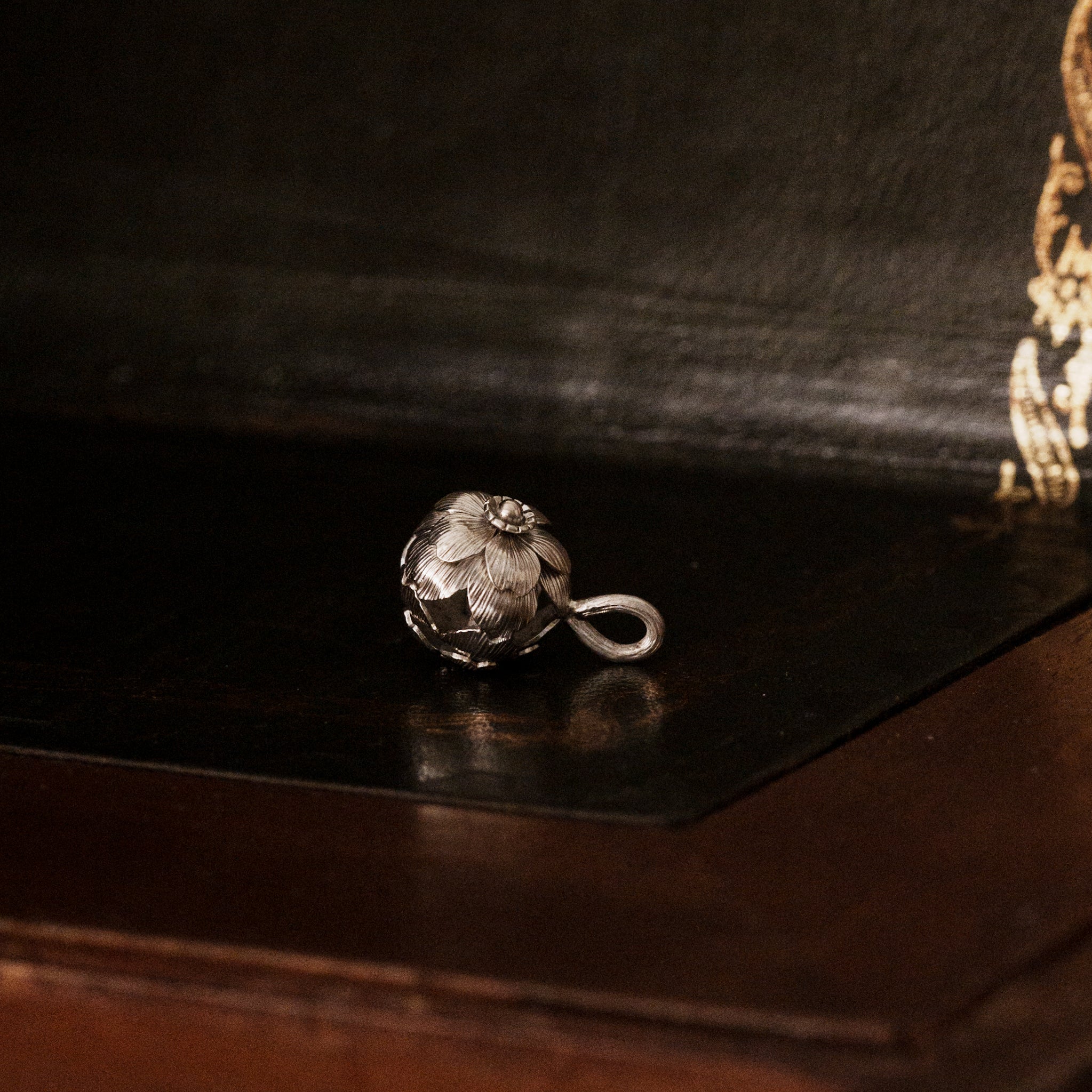 a 925 sterling silver sakura flower-shaped pendant lying down on a dark wooden surface