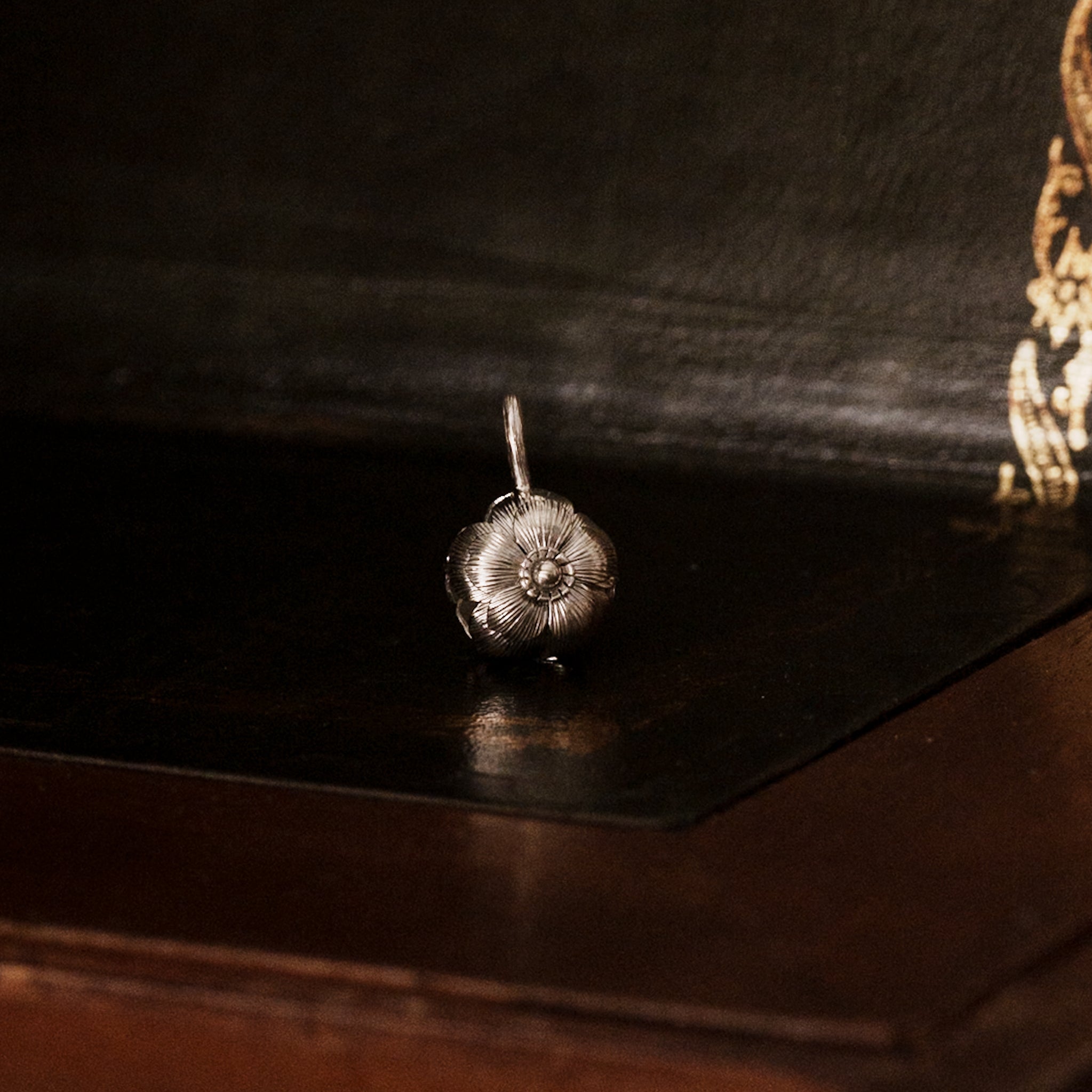 925 sterling silver sakura flower-shaped pendant on a dark wooden surface